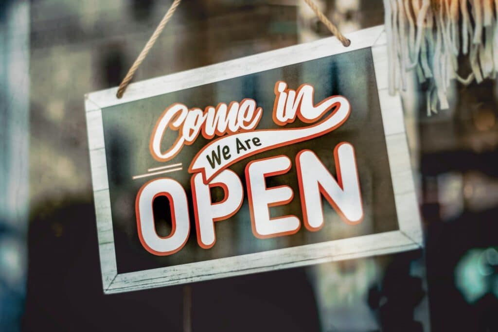 Come in, we are open sign hanging in a business storefront window