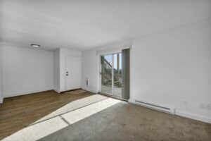 Empty rental apartment after a tenant moved out, with carpet, wood floor and a sliding glass door